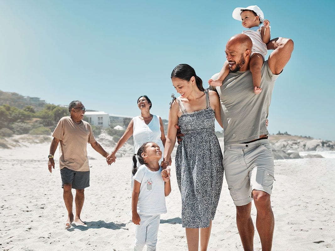 Three generations of a family walking together along a beach.